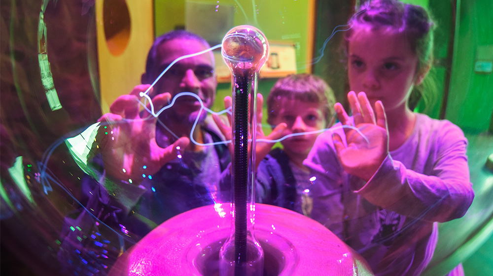 deux enfants et un adulte, jouant avec la boule à plasma