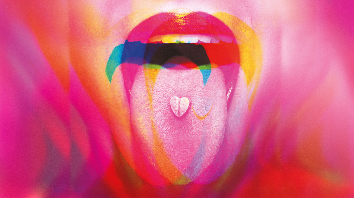 langue tirée, avec un "bonbon" sur la langue. l'image est rose et floue