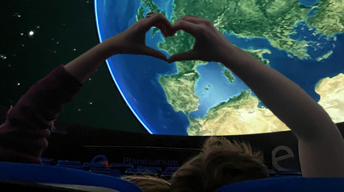 deux personnes au planetarium, formant un coeur avec leurs mains