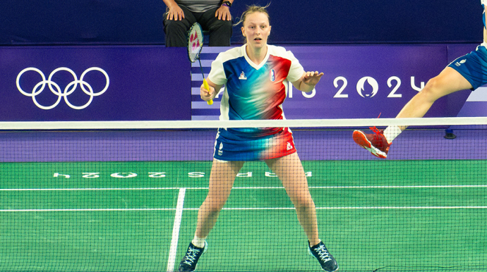 Photo d'une joueuse de badminton, raquette en main, devant le filet