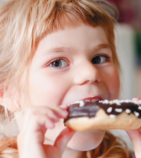 petite fille qui croque un beignet