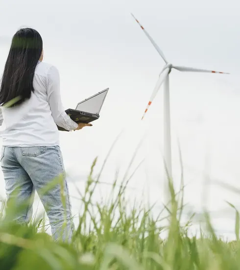 photo d'une femme dans un champs d'herbe, regardant une éolienne
